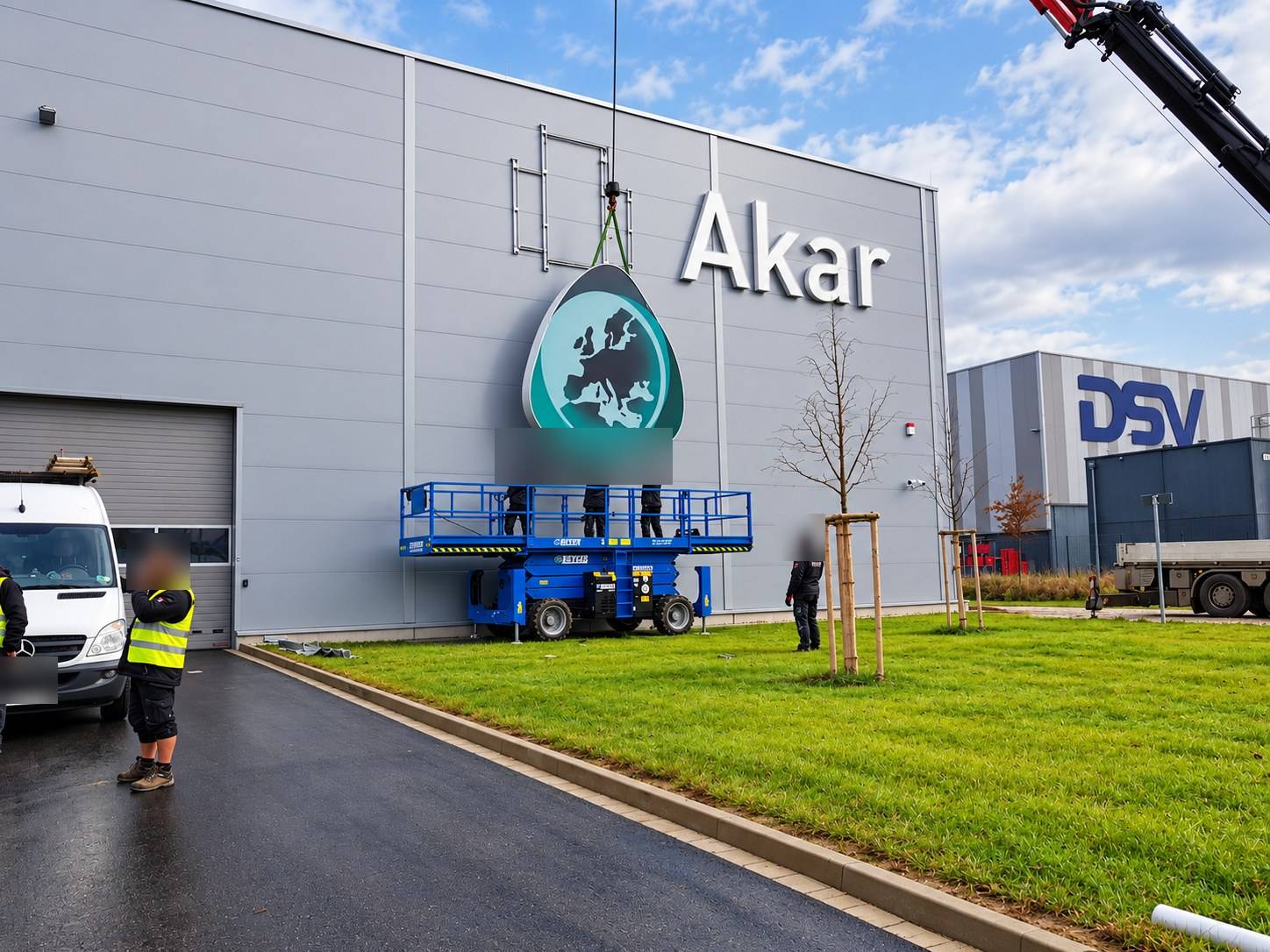 Installing the Akar illuminated logo with a crane and aerial platform on a logistics hall