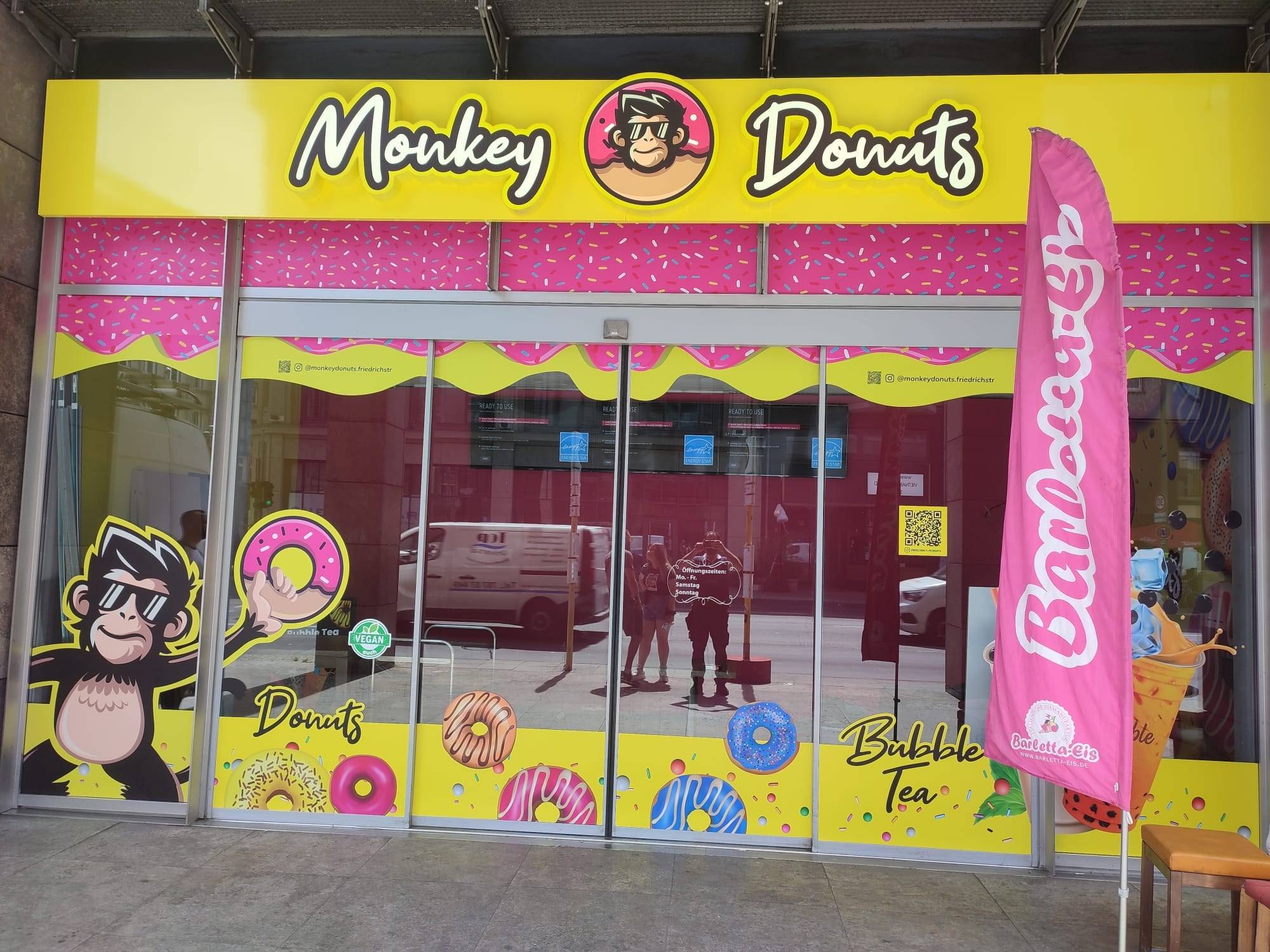 Monkey Donuts shopfront with illuminated lettering, window graphics and beach flag