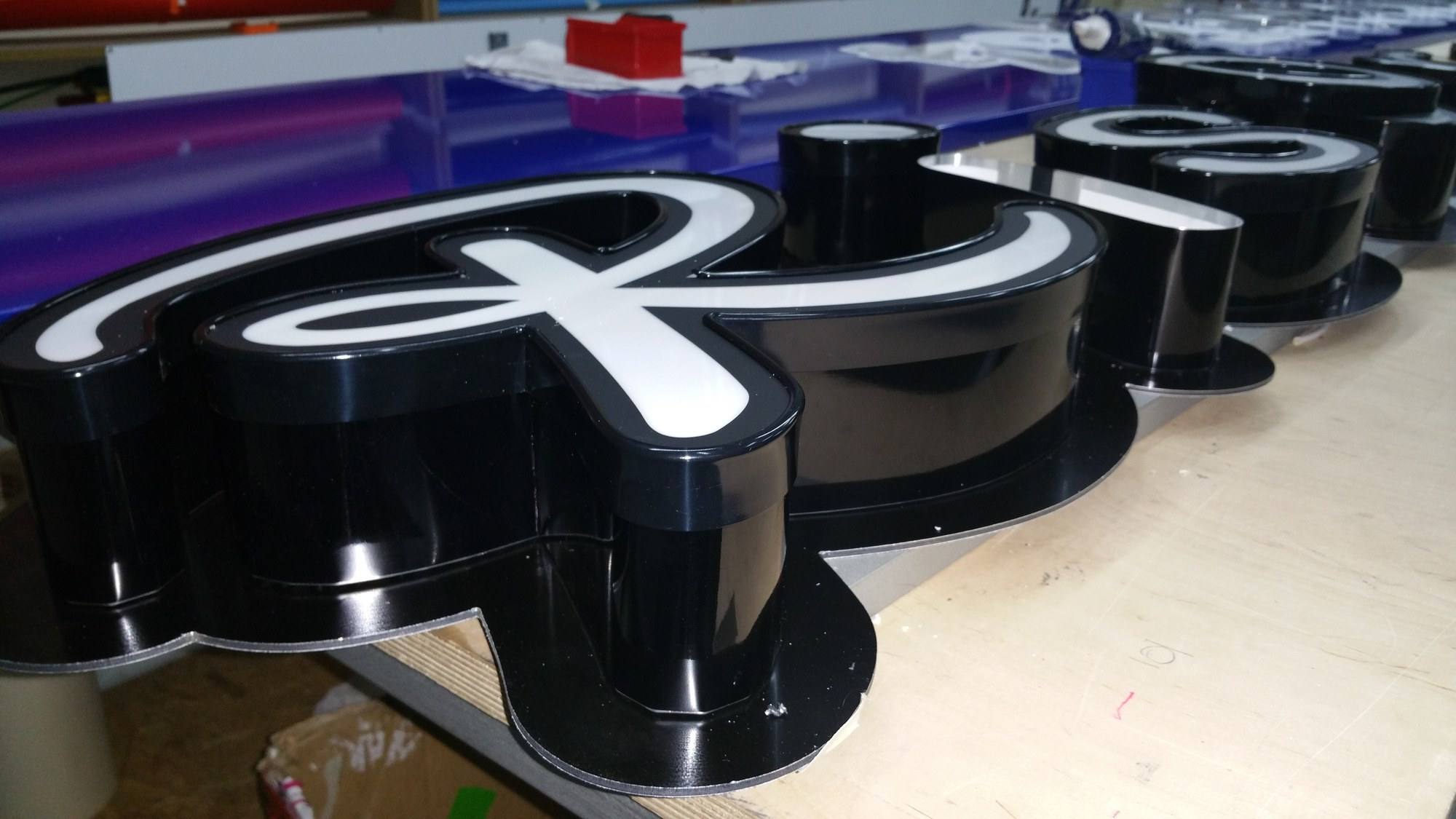 Schwarze Profilbuchstaben mit weißer Leuchtfläche in der Werkstatt, fertig zur Montage