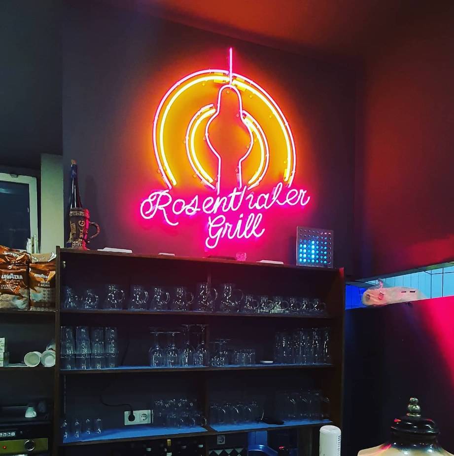 Neon sign “Rosenthaler Grill” with TV tower motif in pink and yellow above a bar