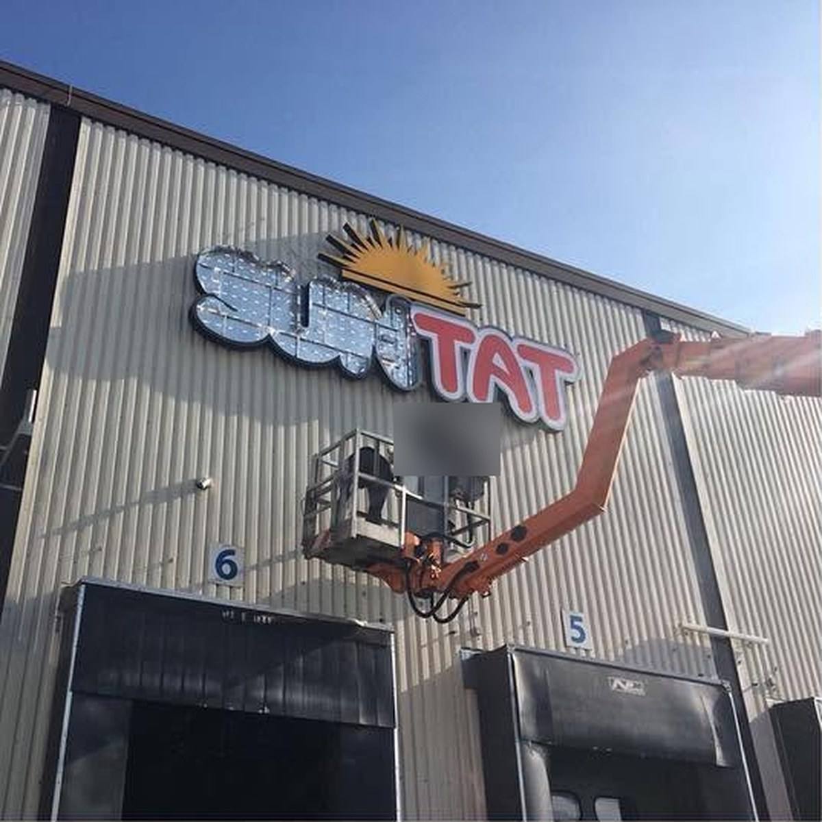 Montage der Suntat-Buchstaben mit Hubarbeitsbühne an der Lagerhalle, LED-Module noch sichtbar