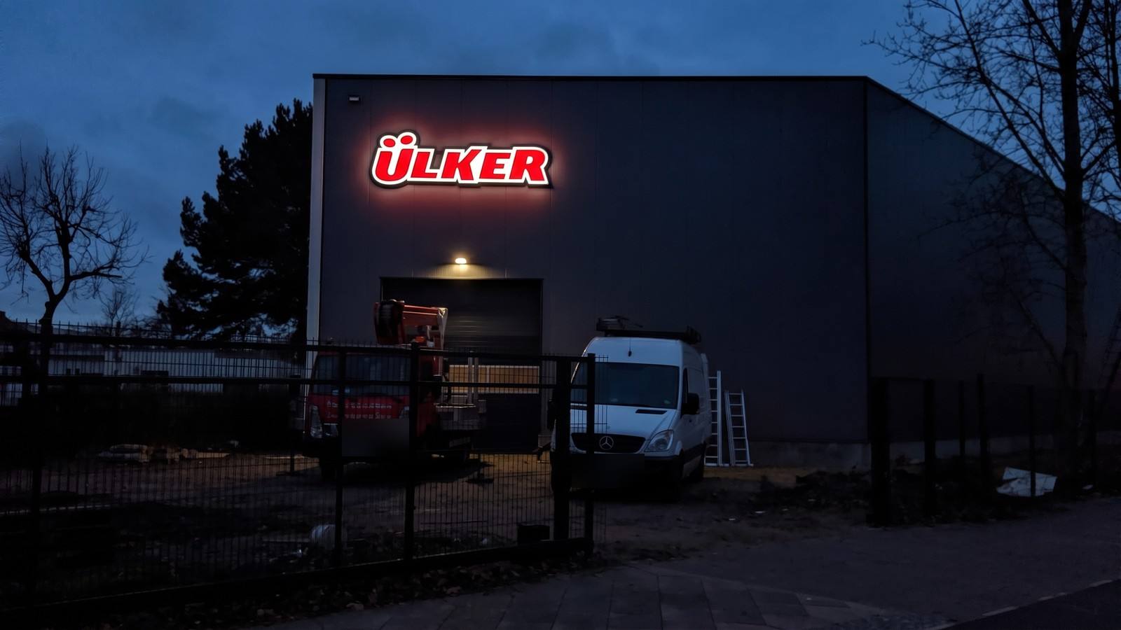 Dieselbe Halle als Nachtansicht visualisiert: Schriftzug leuchtet rot-weiß