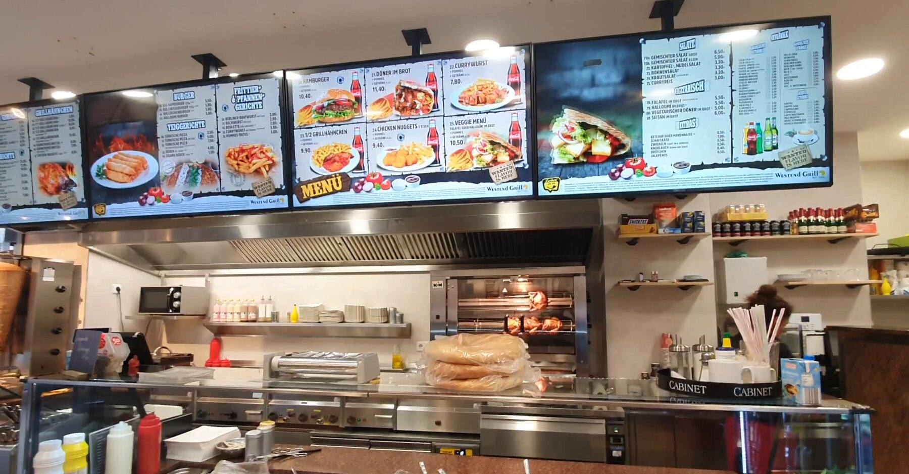 Theke von Westend Grill mit vier Menübildschirmen über der Küche, Inhalte aus WSCREEN