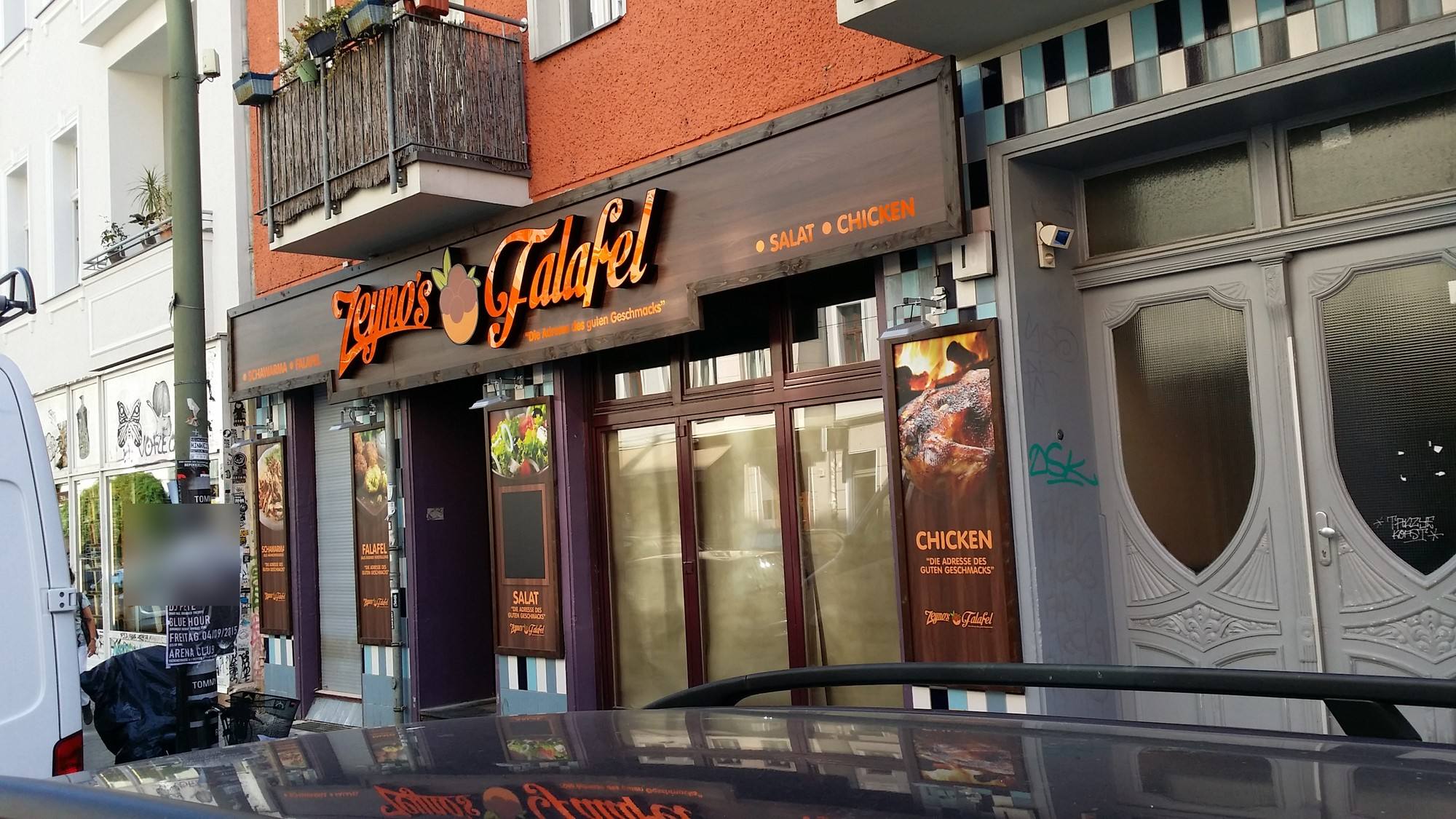 Imbissfassade mit Schriftzug „Zeyno’s Falafel“ und Werbetafeln bei Tag